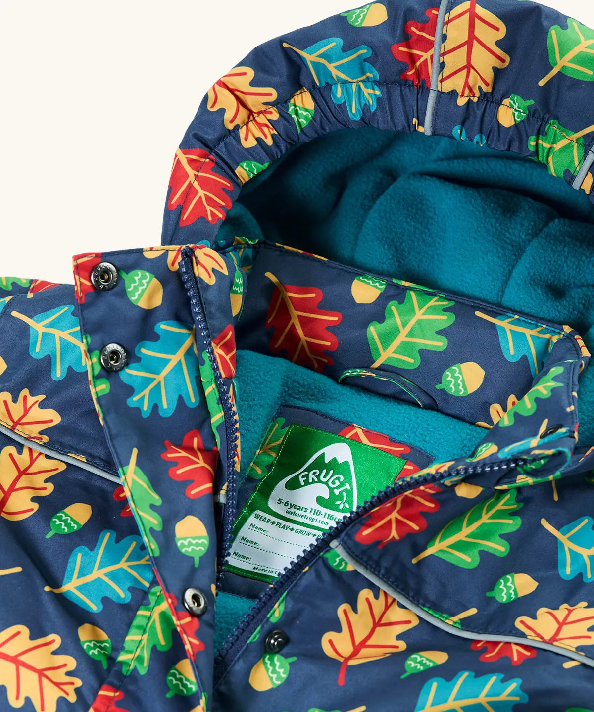 Frugi children's playtime waterproof coat with a multi-coloured acorn tumble print on a navy background, close up of zipper front and popper closures to neck