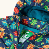 Frugi children's playtime waterproof coat with a multi-coloured acorn tumble print on a navy background, close up of zipper front and popper closures to neck