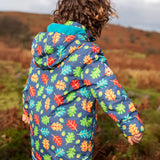 Back of small child wearing the Frugi playtime waterproof coat in navy with a repeating multicoloured acorn design. Showing the hood is down. 