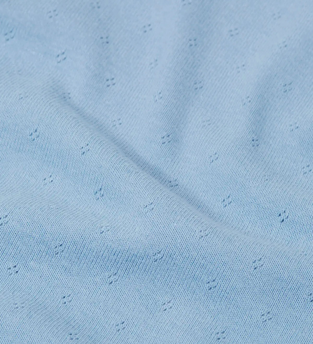 Close up of the organic cotton material of the Frugi pointelle long sleeved baby body in winter sky blue. 