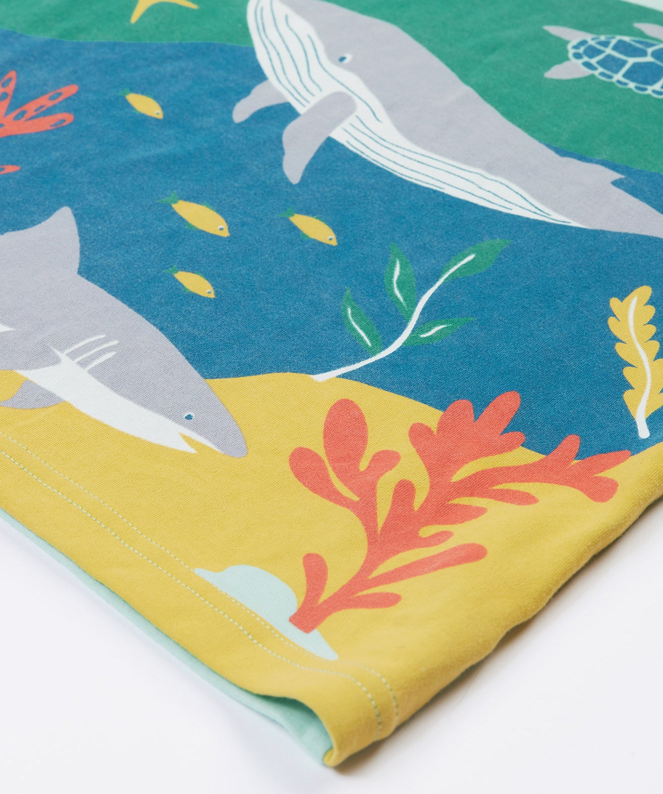 A close up of Frugi Iori Printed T-Shirt in Spring Mint's colourful Sea Life Scene which includes whales, sharks and other smaller fish and coral. 
