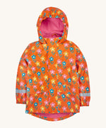 Frugi kids puddle buster coat in fun flowers. A orange waterproof hooded coat with multiple playful prints of flowers with faces and a pink fleece on the inside. Features 2 side pockets, reflective strips on the wrist cuffs and a hook on the inside to hang up.