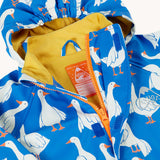 A close up of the top of the orange zip opening on the Frugi cobalt blue rain jacket with all over goose print. The jacket has a yellow jersey lining and a label underneath the hanging loop inside with space to write names. 