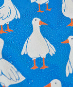A close up of a white goose on the material of the Frugi cobalt blue coloured rain jacket, rain drops can be seen pooling on the jacket. 