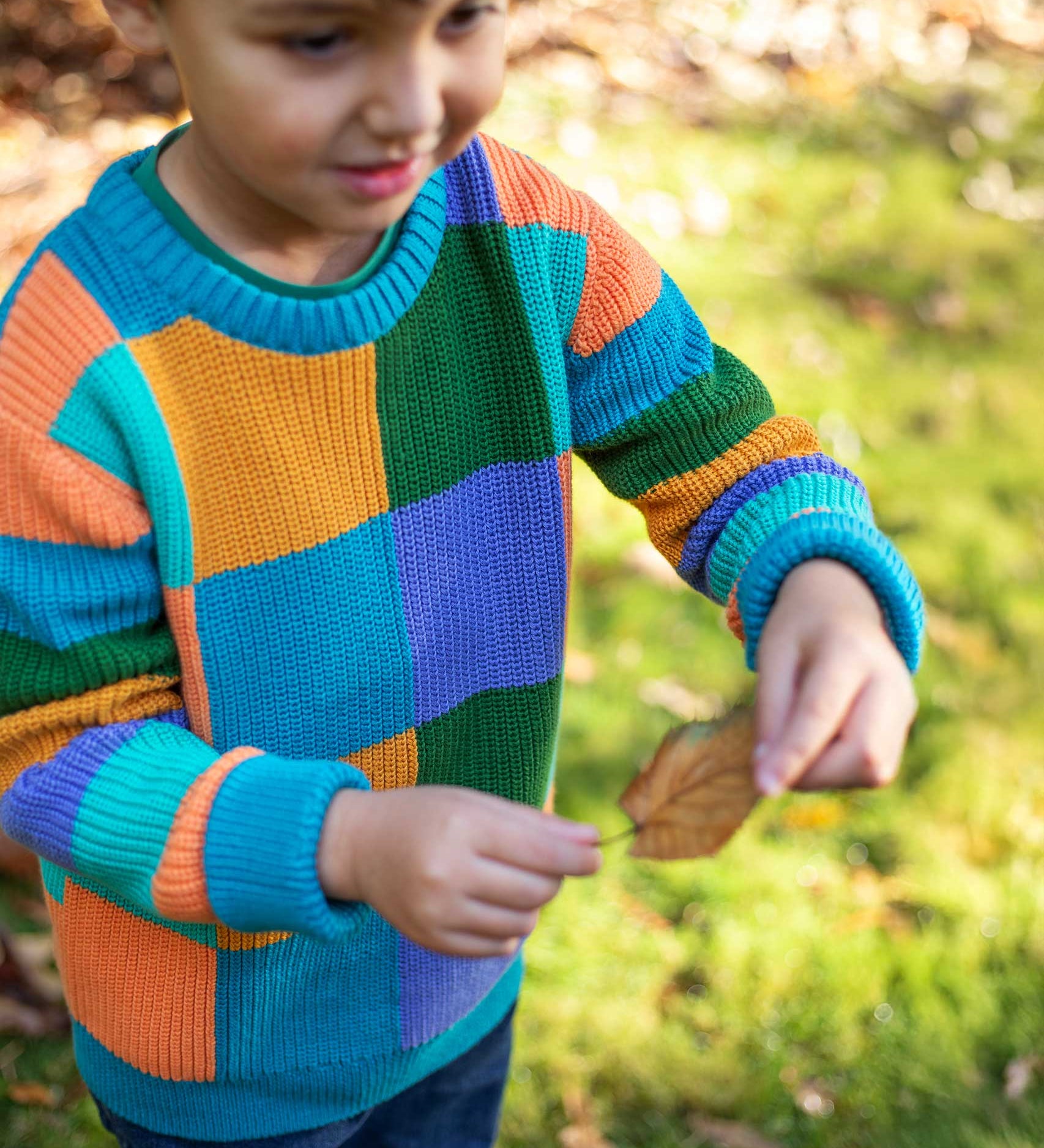 A child wearing the Frugi Rainbow Checkerboard Children's Organic Cotton Knitted Jumper. This knitted kids jumper is part of a wide range of organic cotton clothing for children available here at Babipur. 