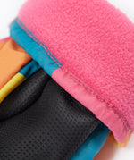 A close up of the Frugi kids rainbow check snow mittens showing the black grippy palm and pink fleece inner for warmth 