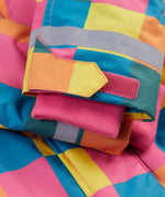 A close up of the Frugi kids snow and ski coat in rainbow check showing the pink storm cuff detail and reflective strips