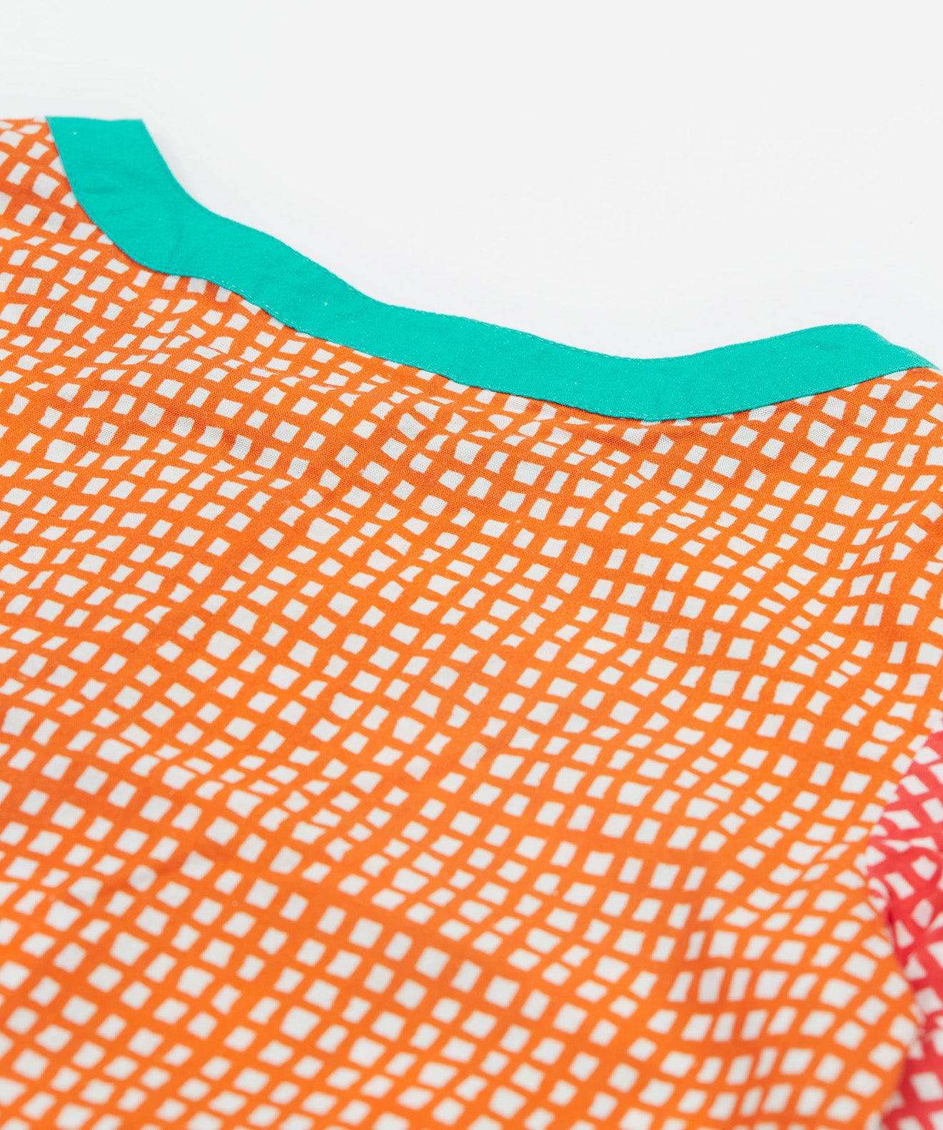 A close up of Frugi Estella Shirt, with a Rainbow Hotchpotch print, featuring orange patterns and a mint collar.