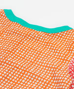 A close up of Frugi Estella Shirt, with a Rainbow Hotchpotch print, featuring orange patterns and a mint collar.