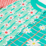 A close up of Frugi Estella Shirt, with a Rainbow Hotchpotch print, including daisies on striped green and mint backgrounds with white buttons down the middle.