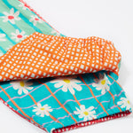 A close up of the bottom of the Frugi Summer Printed Dungaree in the Rainbow Hotchpotch print, folded.