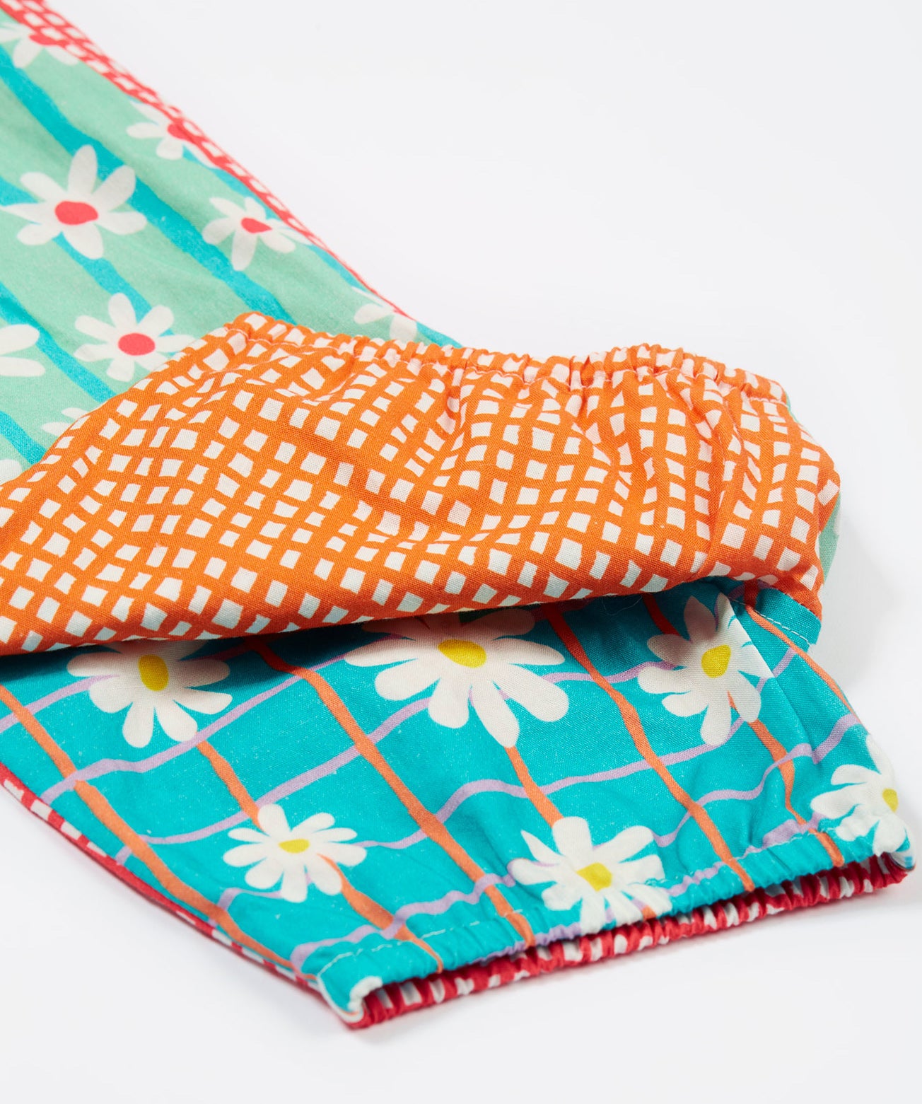 A close up of the bottom of the Frugi Summer Printed Dungaree in the Rainbow Hotchpotch print, folded.
