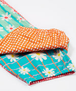 A close up of the bottom of the Frugi Summer Printed Dungaree in the Rainbow Hotchpotch print, folded.
