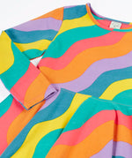 Close up of the Frugi GOTS organic cotton long sleeved sofia skater dress with a rainbow ric rac pattern.