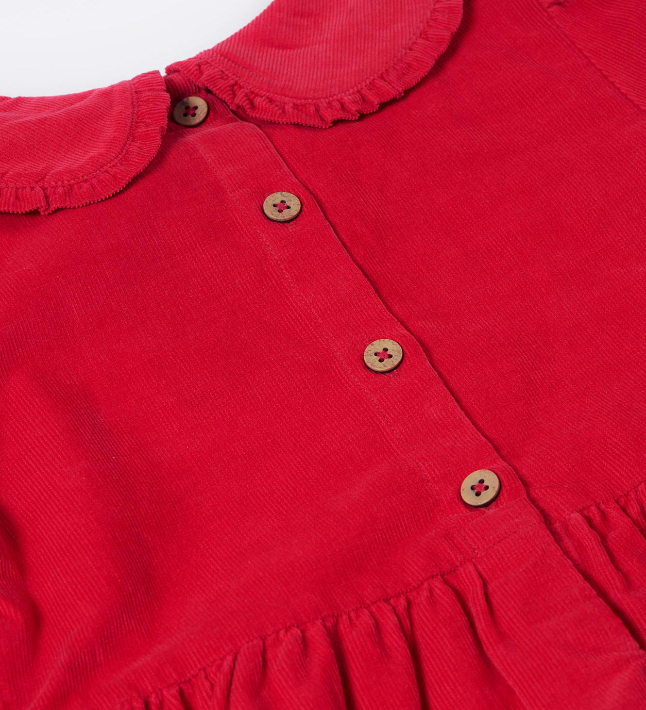 A close up of the button closure on the back of the Frugi Red Robin Corduroy Kids' Christmas Organic Dress. This red cord dress is a part of a wide range of organic cotton clothing for children available here at Babipur. 