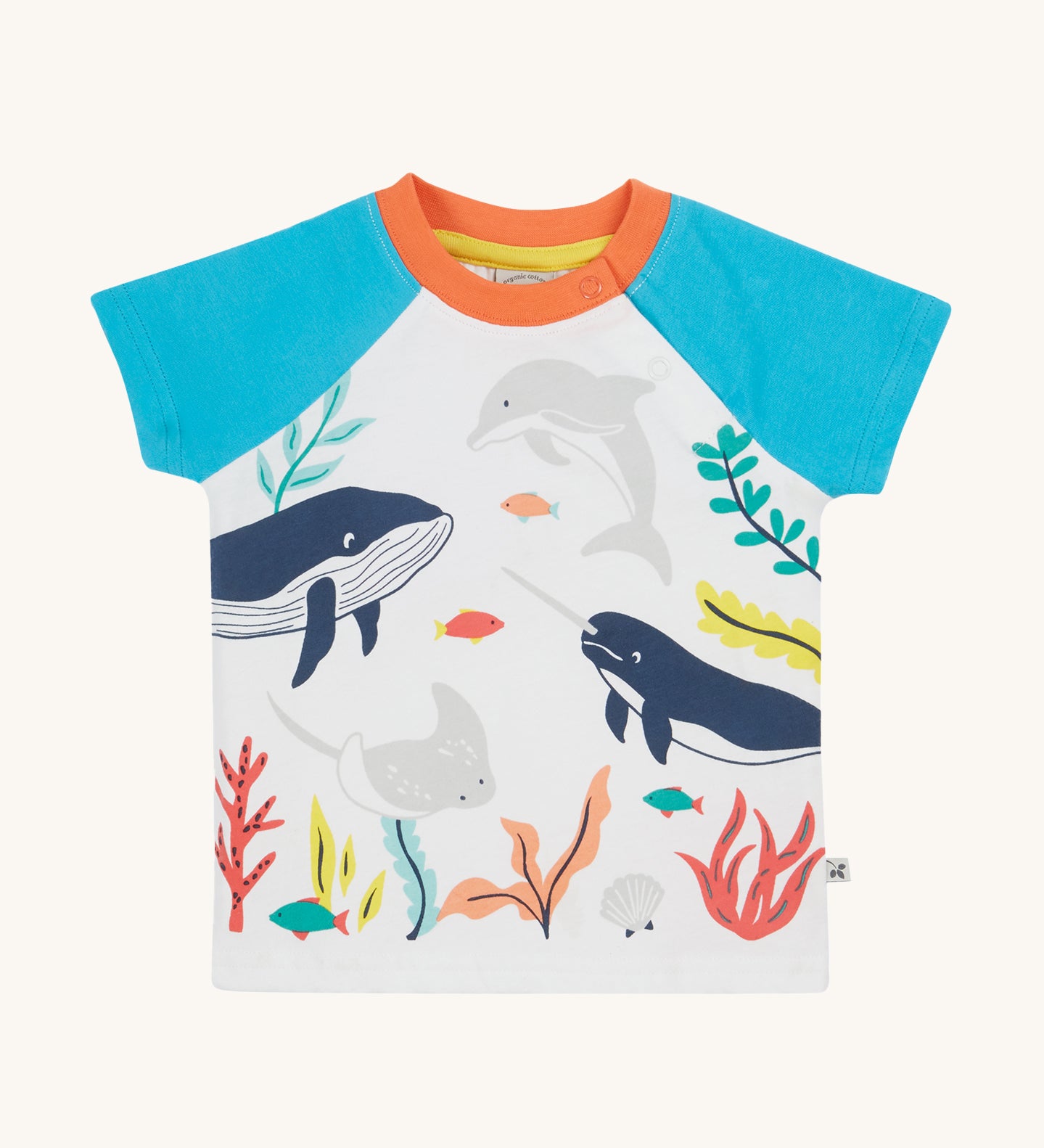 Frugi Reid Raglan T-Shirt in Soft White laid flat, featuring a Sea Life Whale print, which includes large sea animals such as the whale, and smaller fish surrounded by colourful seaweed and coral, with blue sleeves and a orange collar with popper fastenings.