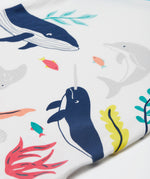 A close up of Frugi Reid Raglan T-Shirt in Soft White, featuring a Sea Life Whale print, which includes large sea animals such as the whale, and smaller fish surrounded by colourful seaweed and coral.