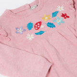 A close up of the Frugi kids remi knitted romper in pink marl /flowers showing the woodland inspired embroidery detail.
