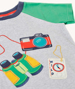 Close up of front of the Frugi raglan t-shirt featuring an adventure themed applique design on the front with a pair of green binoculars, camera and a wild card compass. 