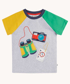 Frugi raglan t-shirt in a grey marl colour with one green and one yellow sleeve and an adventure themed applique design on the front featuring a pair of green binoculars, camera and a wild card compass. 