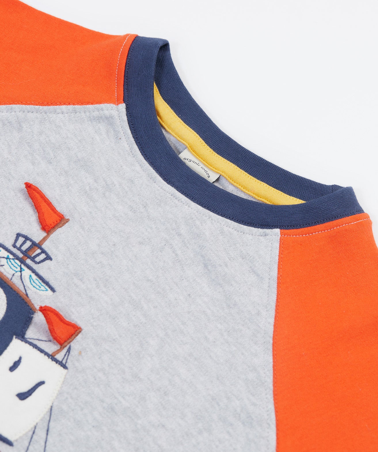 A close up of Frugi Renny Raglan T-Shirt in Grey Marl, featuring orange sleeves with a navy collar.