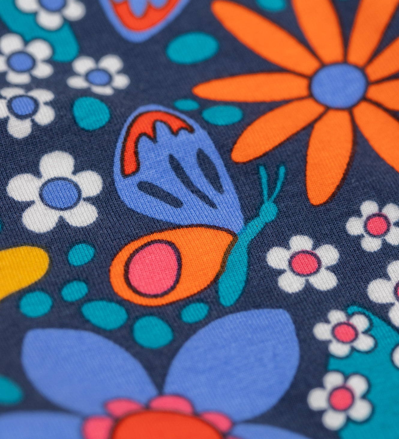 A close up of the print on the Frugi Retro Floral Leona Organic Cotton Kids' Leggings. A navy coloured legging with a bright multicoloured retro style flower print all over. These leggings are part of a wide range of organic cotton clothing for children available here at Babipur. 