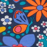 A close up of the print on the Frugi Retro Floral Leona Organic Cotton Kids' Leggings. A navy coloured legging with a bright multicoloured retro style flower print all over. These leggings are part of a wide range of organic cotton clothing for children available here at Babipur. 