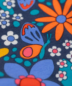 A close up of the print on the Frugi Retro Floral Leona Organic Cotton Kids' Leggings. A navy coloured legging with a bright multicoloured retro style flower print all over. These leggings are part of a wide range of organic cotton clothing for children available here at Babipur. 