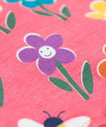 A close up of the Frugi kids reversible helen dungarees in playful flowers. showing the playful flower print detail  on pink organic cotton fabric.