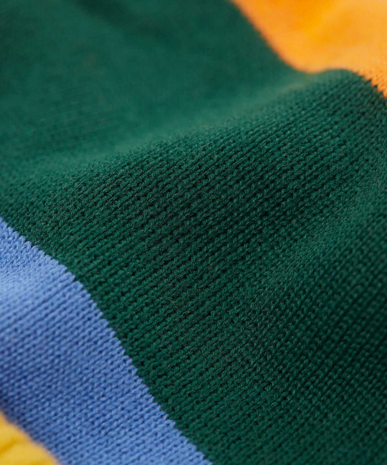 A close up of the penguin/ rainbow Frugi reversible voyager hat showing the bold striped design on GOTS organic cotton fabric.