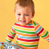 Baby wearing a Frugi rainbow striped long sleeved ribbed organic cotton vest with parsnip pants. 