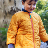 A child wearing the Frugi robin reversible quilted jacket in yellow gold with boat blue fleece.
