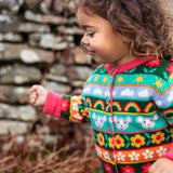 Child wearing the Frugi Robyn fairisle cardigan with a mouse Fair Isle design featuring flowers, rainbows, clouds and suns. 