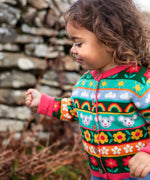 Child wearing the Frugi Robyn fairisle cardigan with a mouse Fair Isle design featuring flowers, rainbows, clouds and suns. 