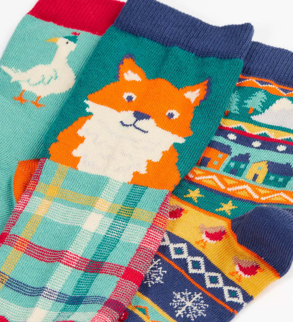 Close up of the Frugi rock my socks 3 pack paw-ty time pet party organic cotton kids socks. One blue pair covered in pets with party hats, one fair isle design, one festive check with red fox.