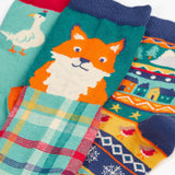 Close up of the Frugi rock my socks 3 pack paw-ty time pet party organic cotton kids socks. One blue pair covered in pets with party hats, one fair isle design, one festive check with red fox.