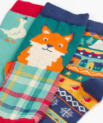 Close up of the Frugi rock my socks 3 pack paw-ty time pet party organic cotton kids socks. One blue pair covered in pets with party hats, one fair isle design, one festive check with red fox.