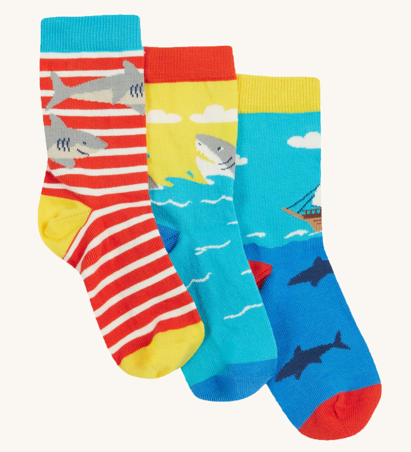 Frugi Rock My Socks 3 Pack laid flat, in the High Seas print. Featuring a bright striped pair, a blue pirate ship pair, and a brilliant shark pair.