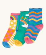 Frugi little roly bamboo socks in a 3 pack with rainbow designs. Rainbow wave stripe pair, green with happy rainbow pair and a patchwork pattern pair.