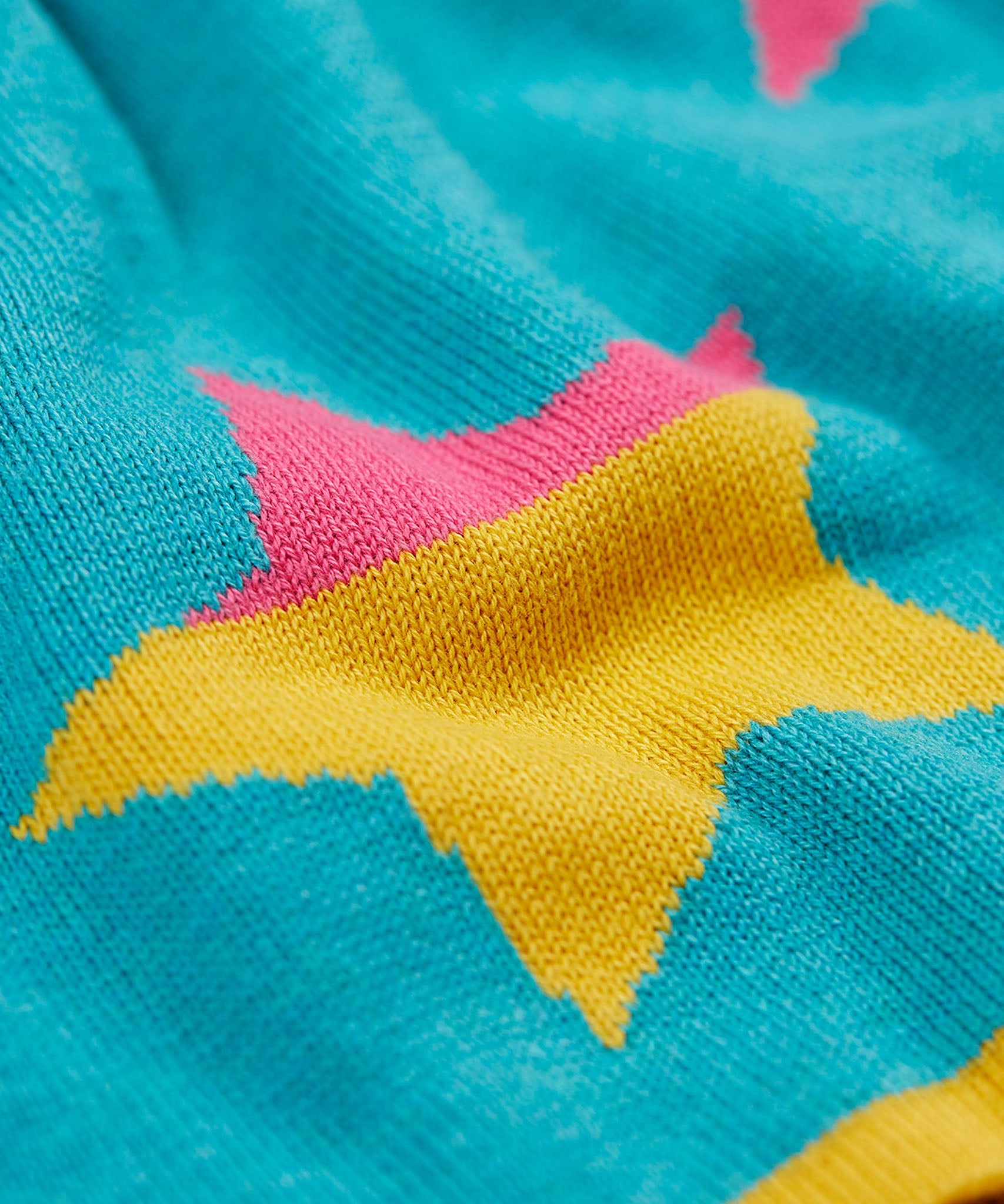 A close up of the multi-coloured striped star on the Frugi Rory Reversible organic cotton kids Skirt with a Rainbow Stars design.