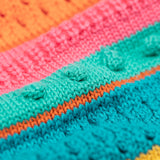 A close up of the Frugi kids rowe rainbow cardigan in rainbow/pointelle showing the soft knit pom pom pattern detail