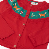 Close up of the Frugi scarlet red organic cotton ishbel embroidered fox cardigan. Red knit child's cardigan with a teal band from shoulder to shoulder decorated with embroidered foxes, holly, toadstools and trees.