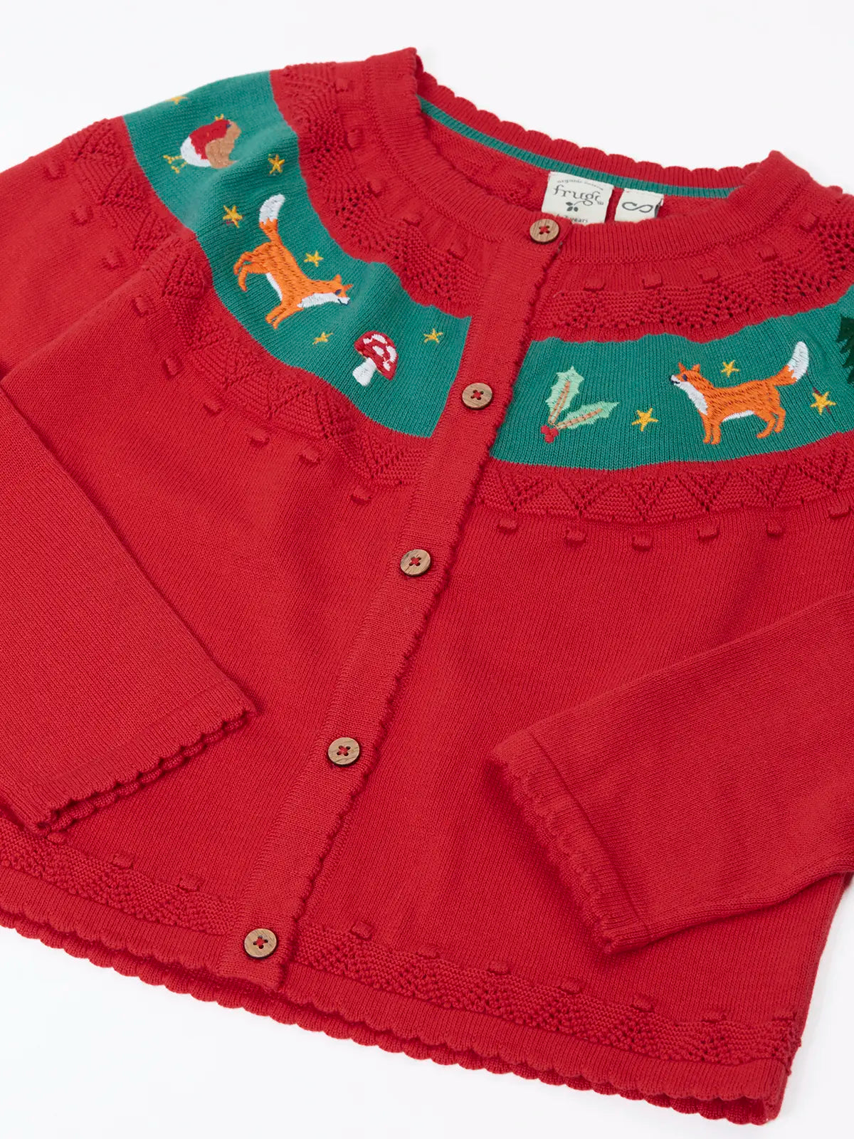 Close up of the Frugi scarlet red organic cotton ishbel embroidered fox cardigan. Red knit child's cardigan with a teal band from shoulder to shoulder decorated with embroidered foxes, holly, toadstools and trees.