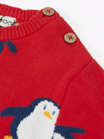 Close up of the wooden buttons on the shoulder of the Frugi scarlet penguins organic cotton jolly knitted jumper. Red knitted jumper with repeat penguin print and rainbow stripe hemline and arm cuffs.