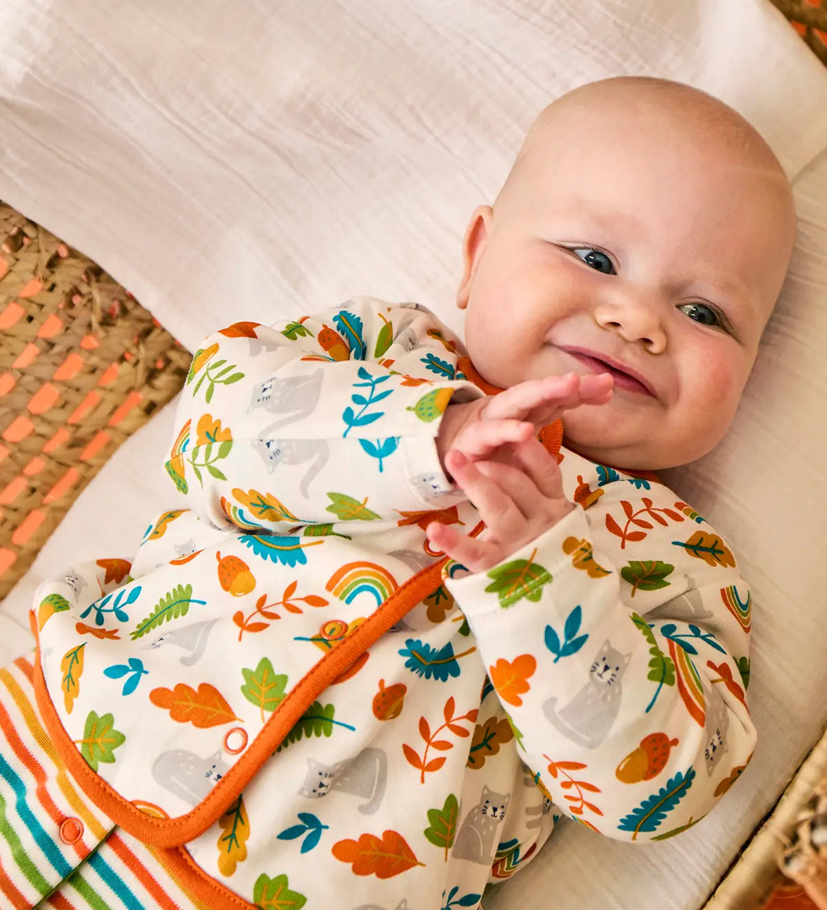 Baby wearing the striped babygrow and wild cats cardigan from the Frugi scrumptious babygrow gift set.