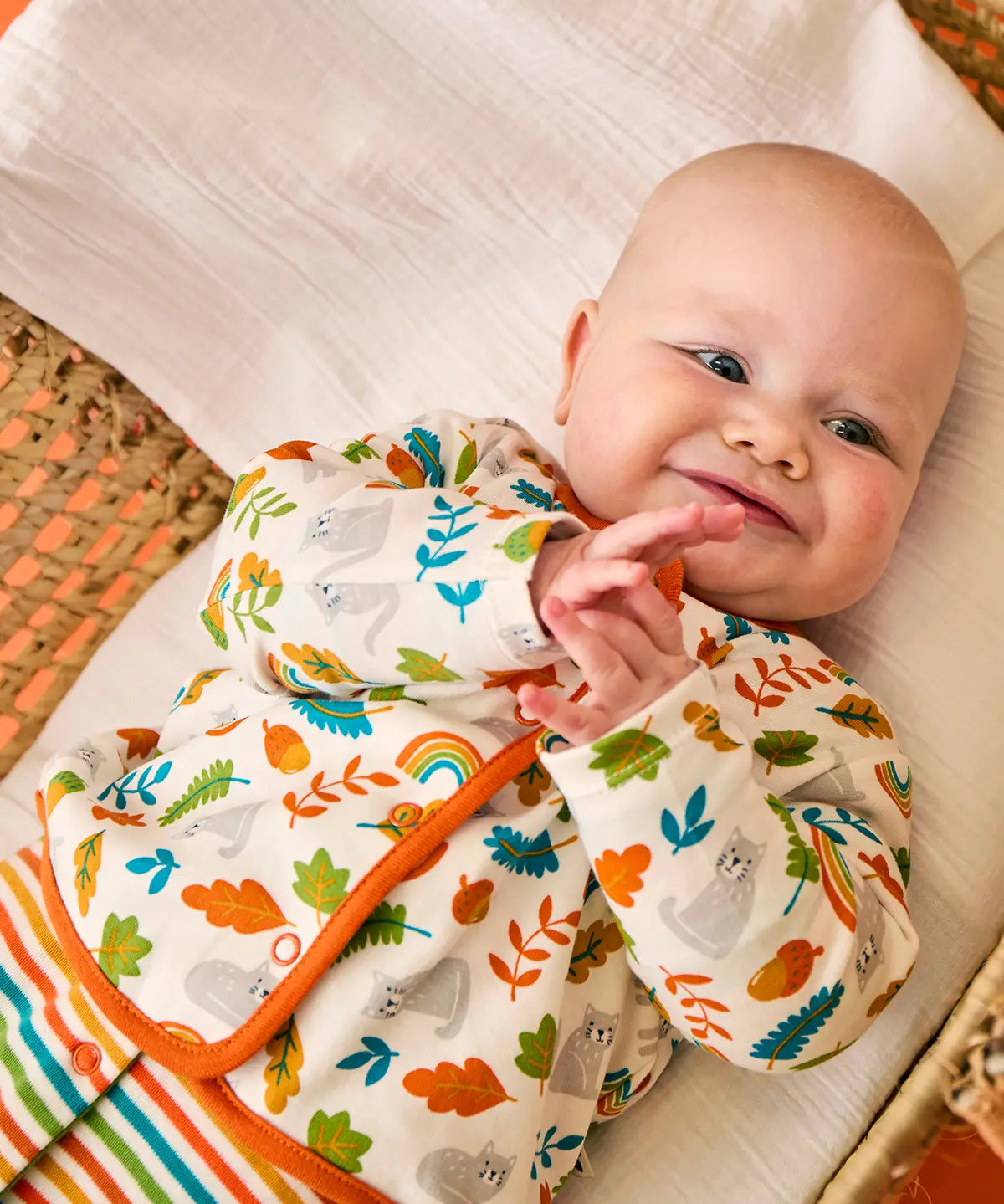 Baby wearing the striped babygrow and wild cats cardigan from the Frugi scrumptious babygrow gift set.