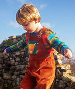 Child wearing the Frugi sebby brown rust organic cotton cord dungaree with a green chest pocket featuring a highland cow applique with a knitted jumper underneath.