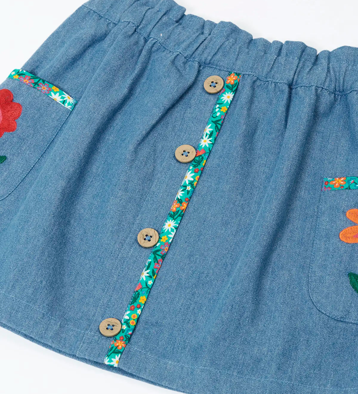 Close up of the buttons on the front of the Frugi Selena child's denim skirt with wildflower trims and wildflower embroidery on the side pockets.