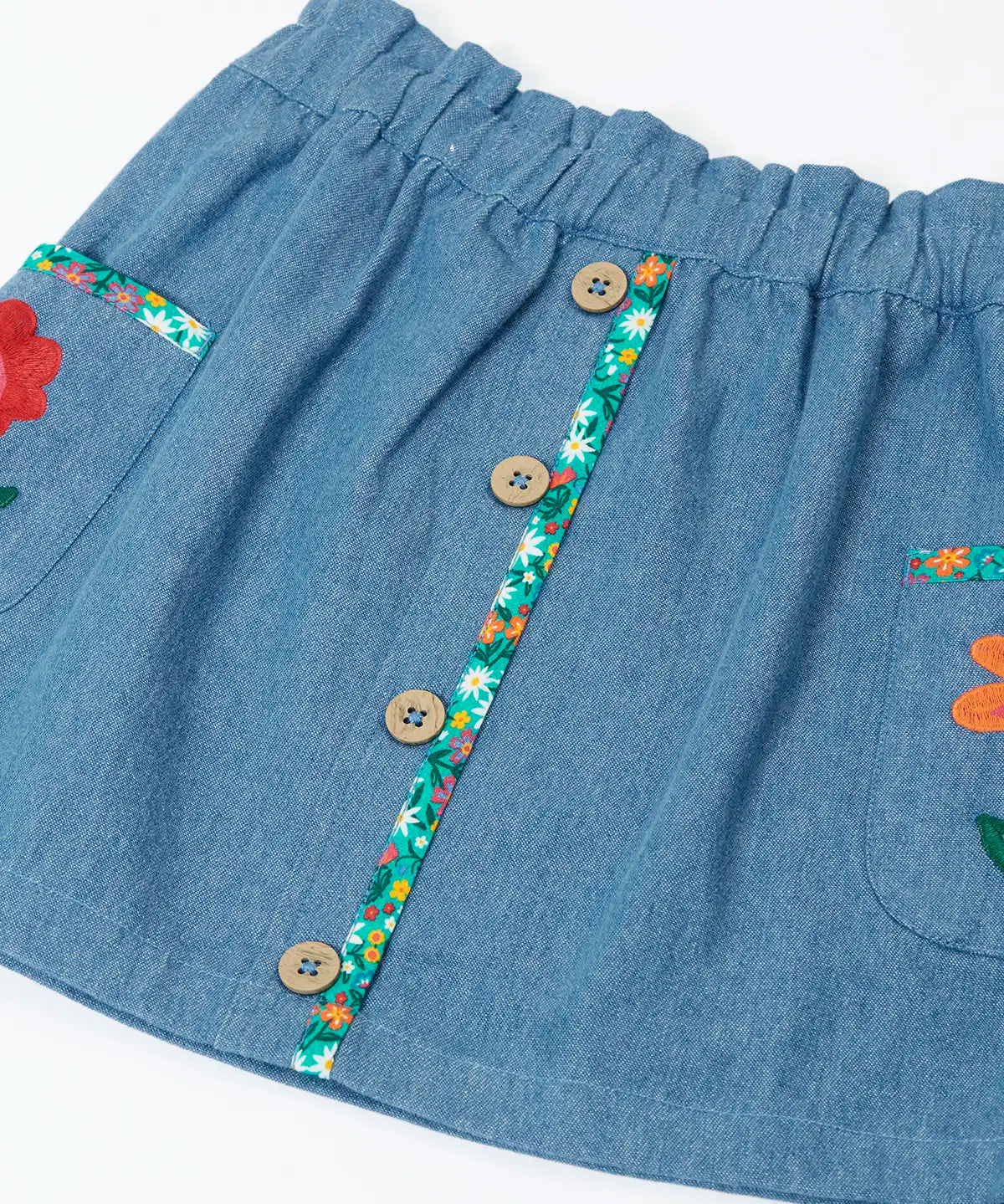 Close up of the buttons on the front of the Frugi Selena child's denim skirt with wildflower trims and wildflower embroidery on the side pockets.