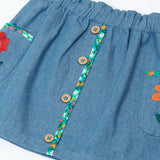 Close up of the buttons on the front of the Frugi Selena child's denim skirt with wildflower trims and wildflower embroidery on the side pockets.